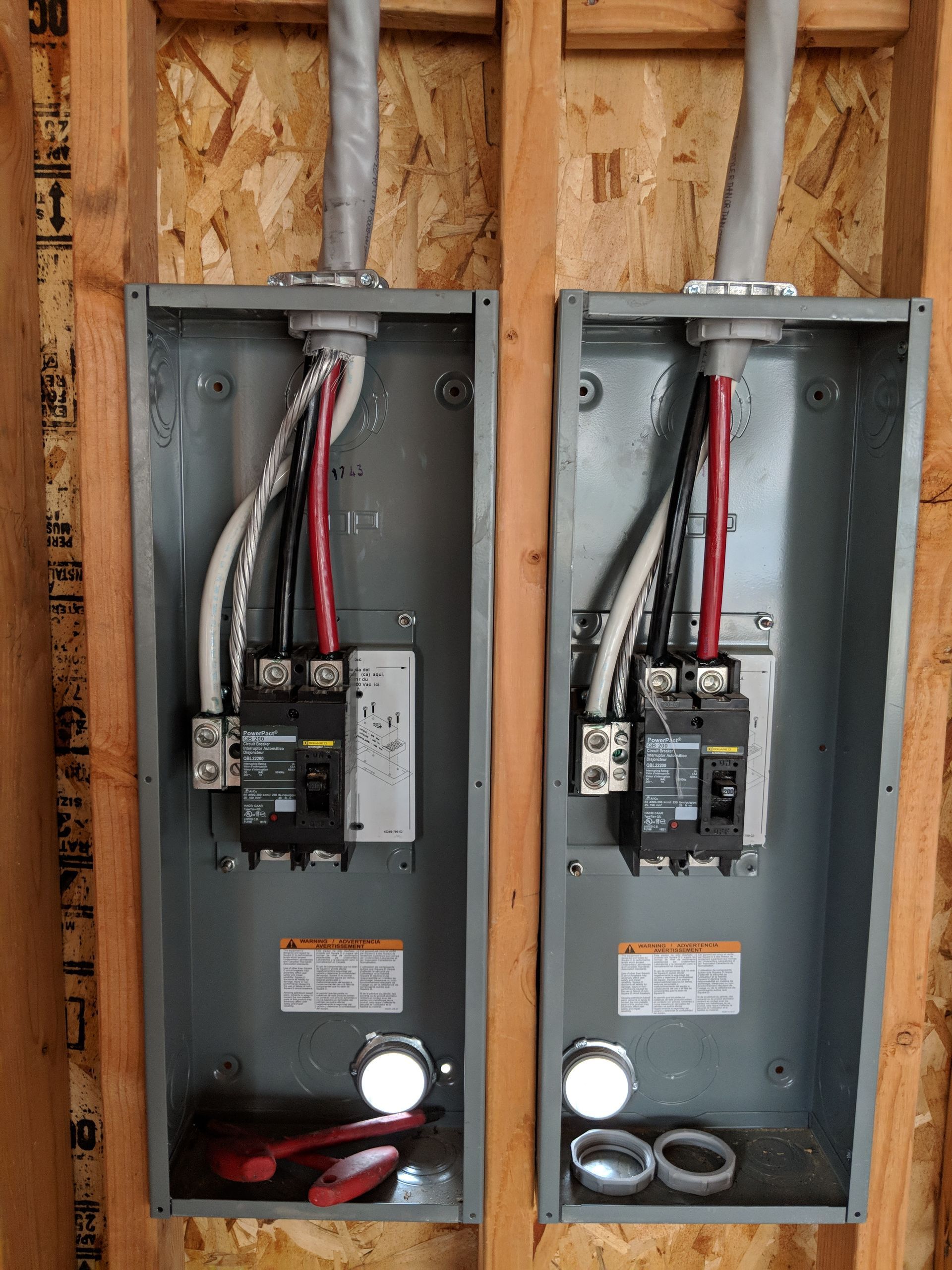 Two electrical boxes are hanging on a wooden wall.