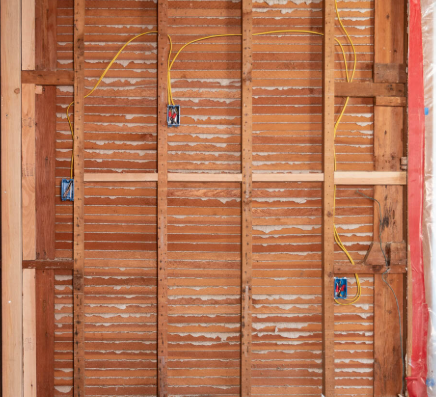 A man is standing on a ladder working on a wall.