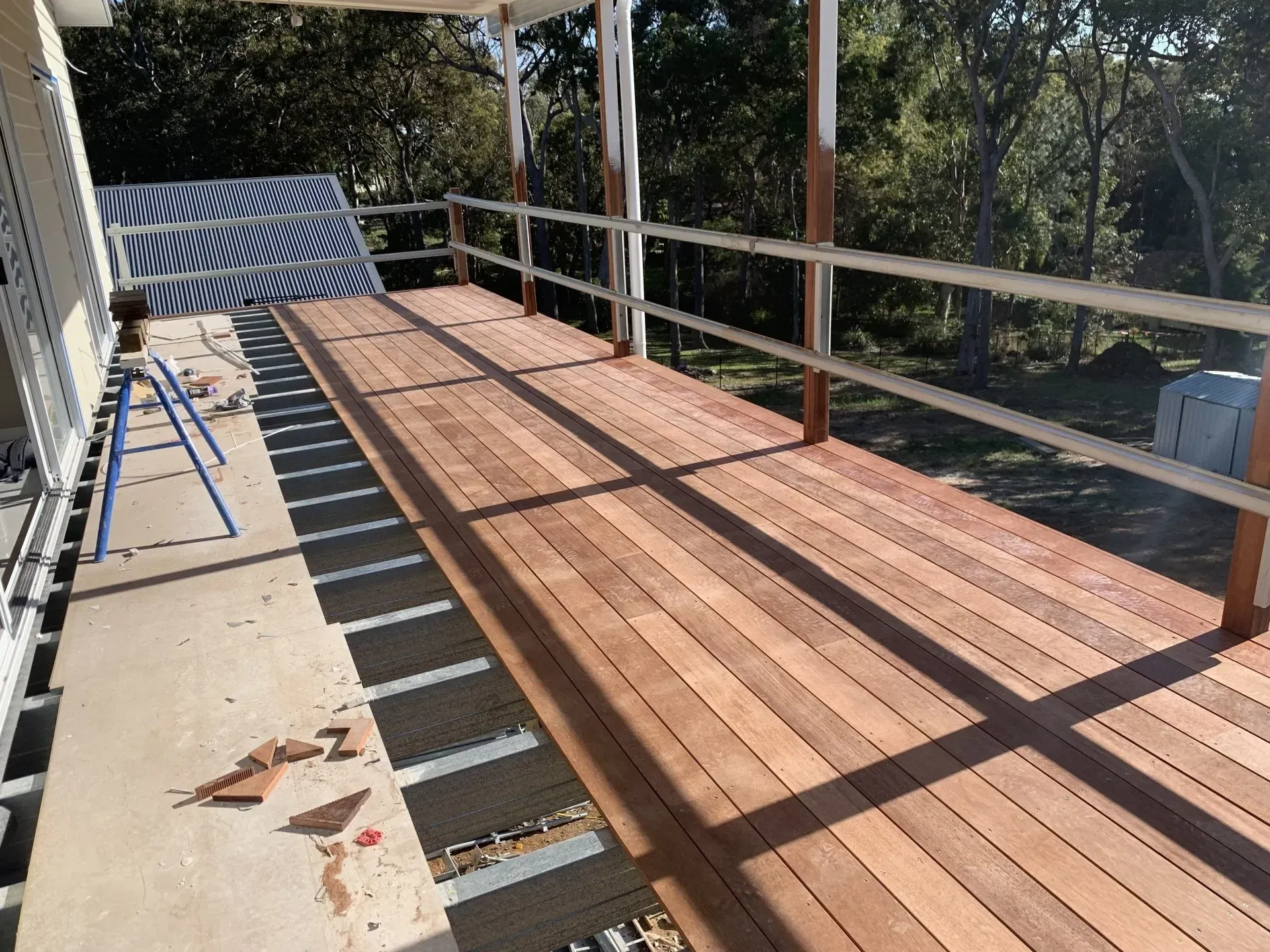 Newly constructed wooden deck with railings, on a sunny day.