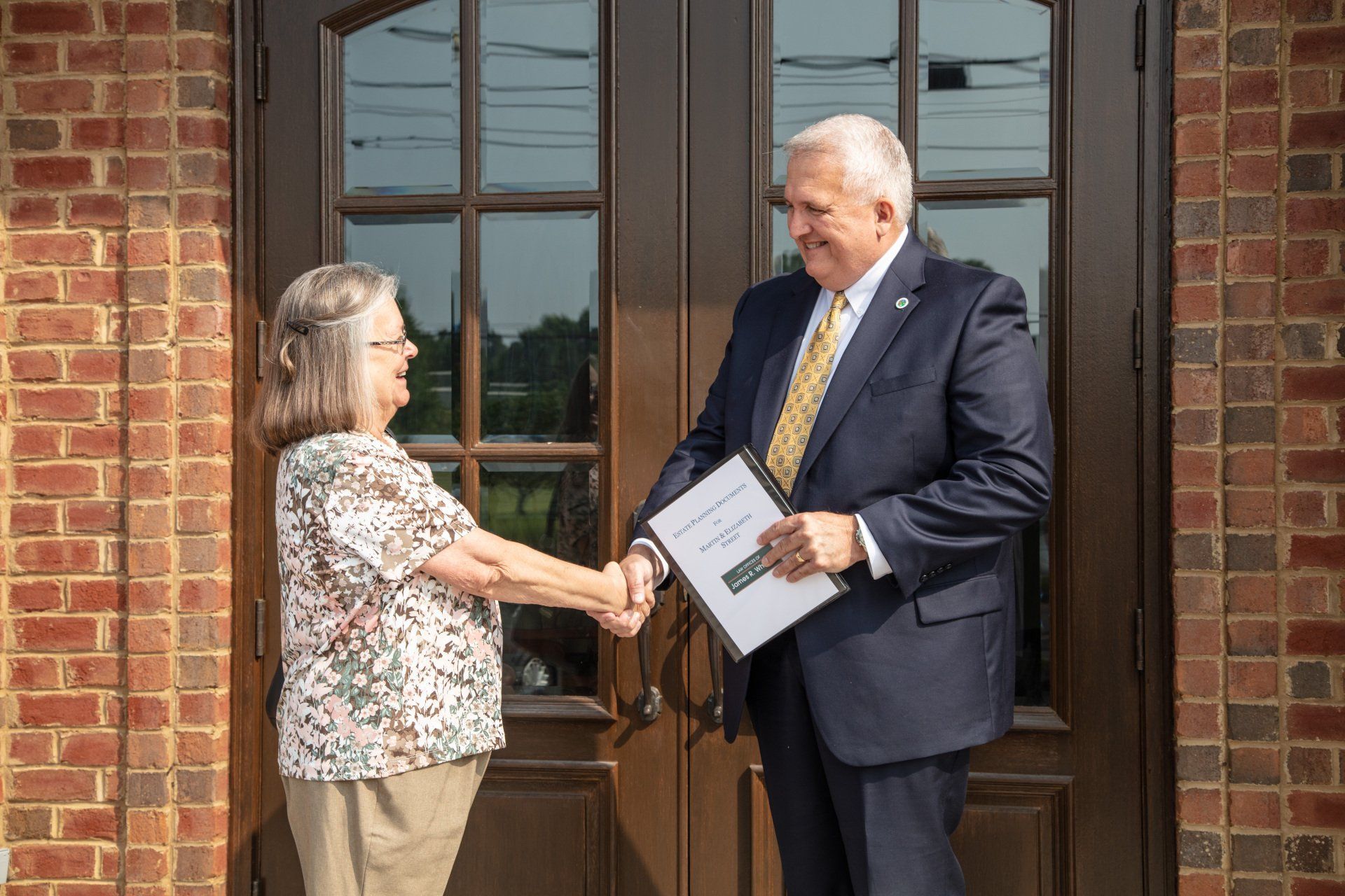 A man in a suit and tie is shaking hands with a woman – Jonesborough, TN - Law Offices of James R Wheeler
