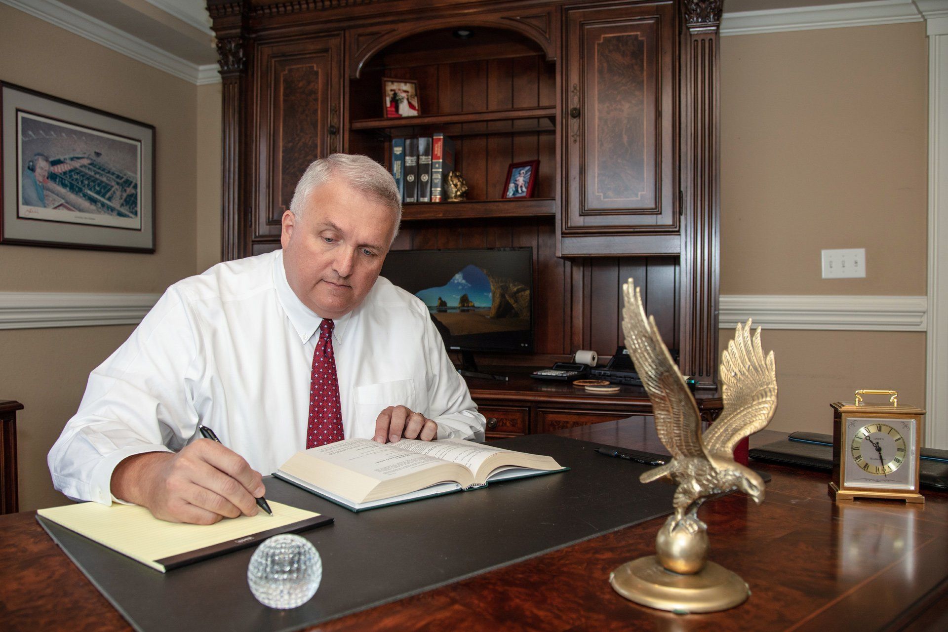 A man is sitting at a desk writing on a piece of paper – Jonesborough, TN - Law Offices of James R Wheeler