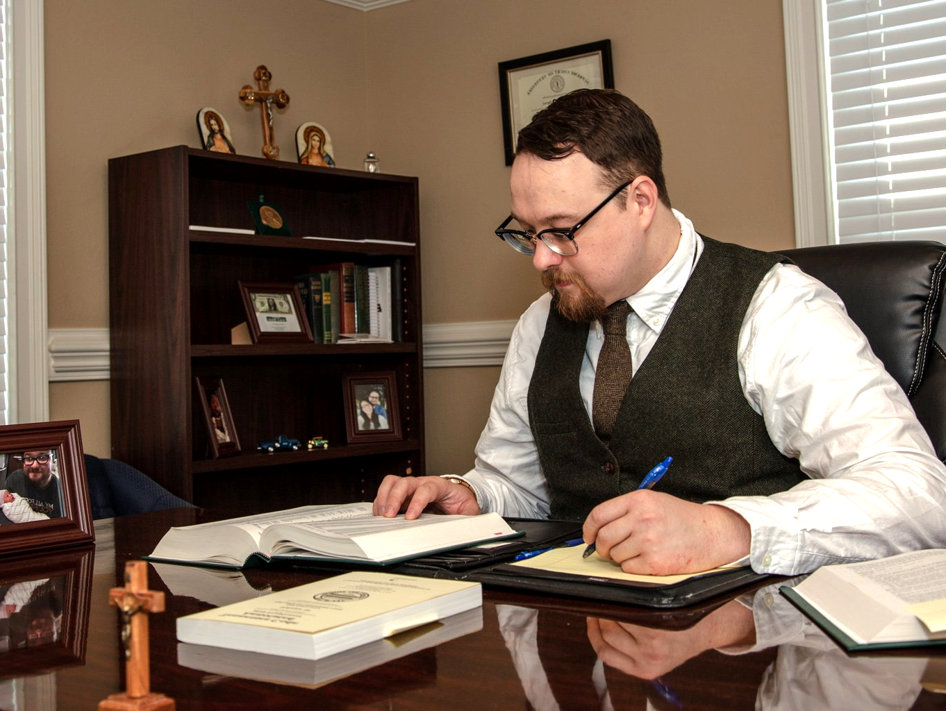 A man is sitting at a desk writing on a piece of paper – Jonesborough, TN - Law Offices of James R Wheeler