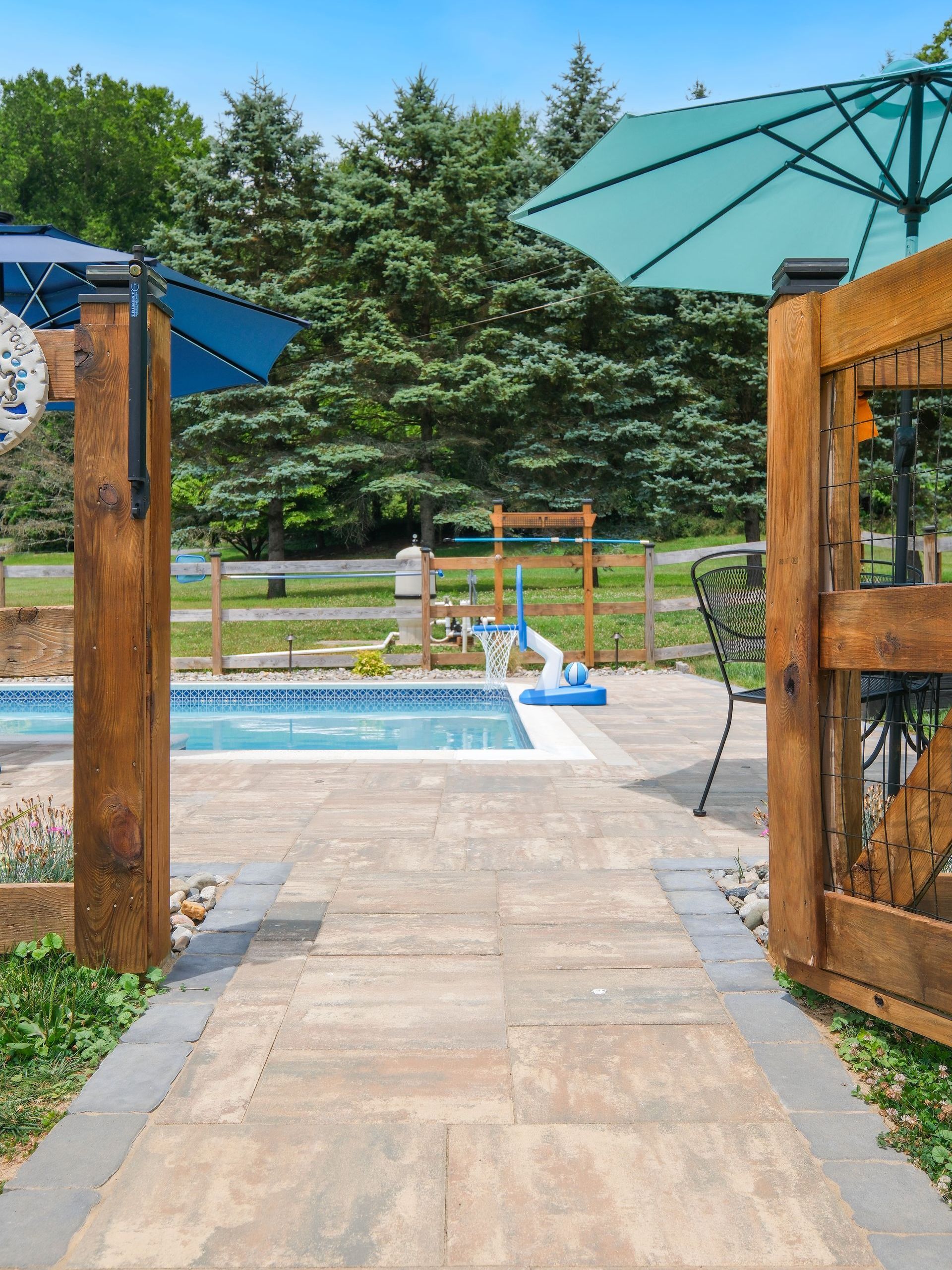 A wooden walkway leading to a swimming pool with umbrellas.