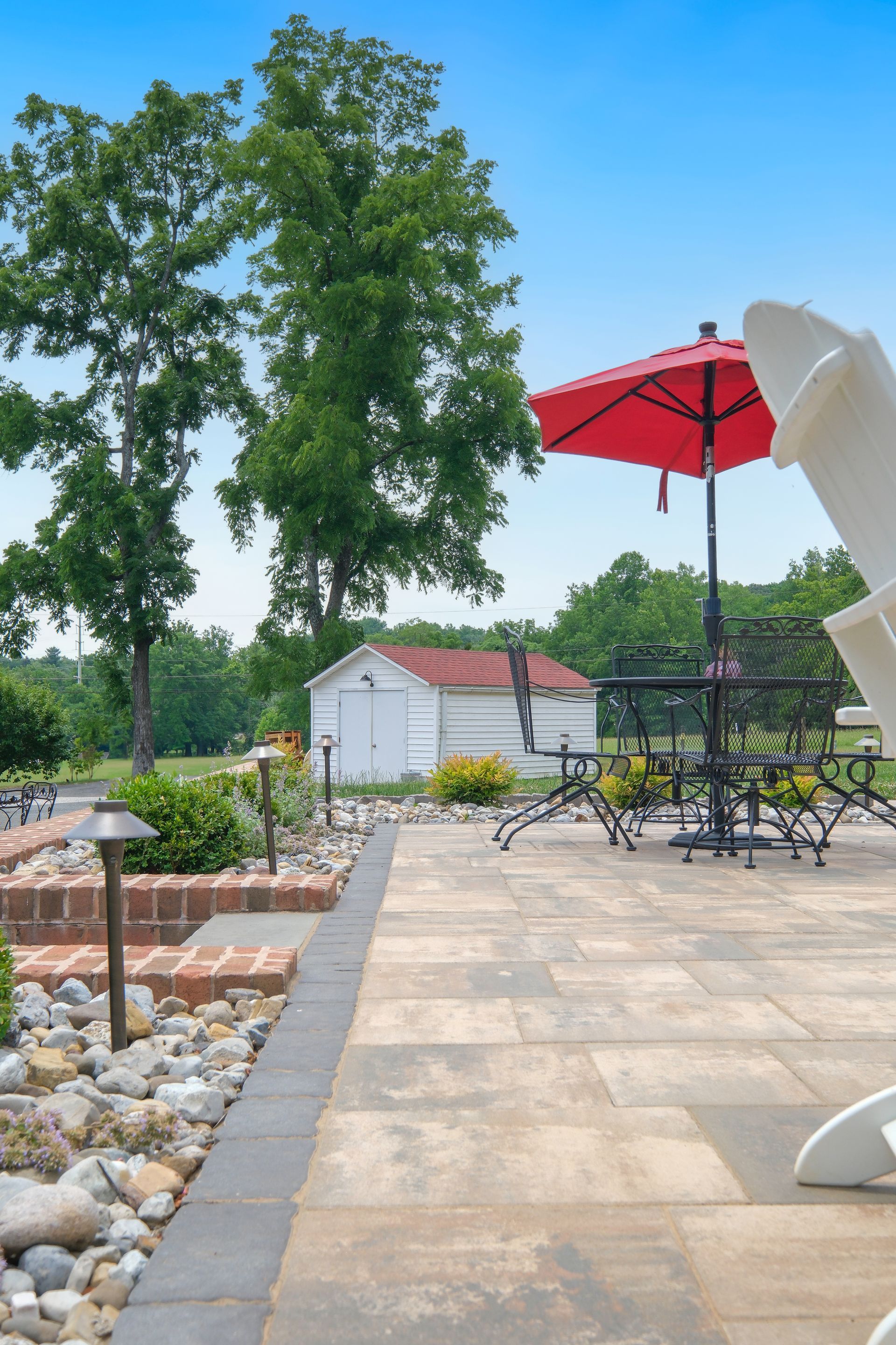 A patio with a table and chairs and a red umbrella.