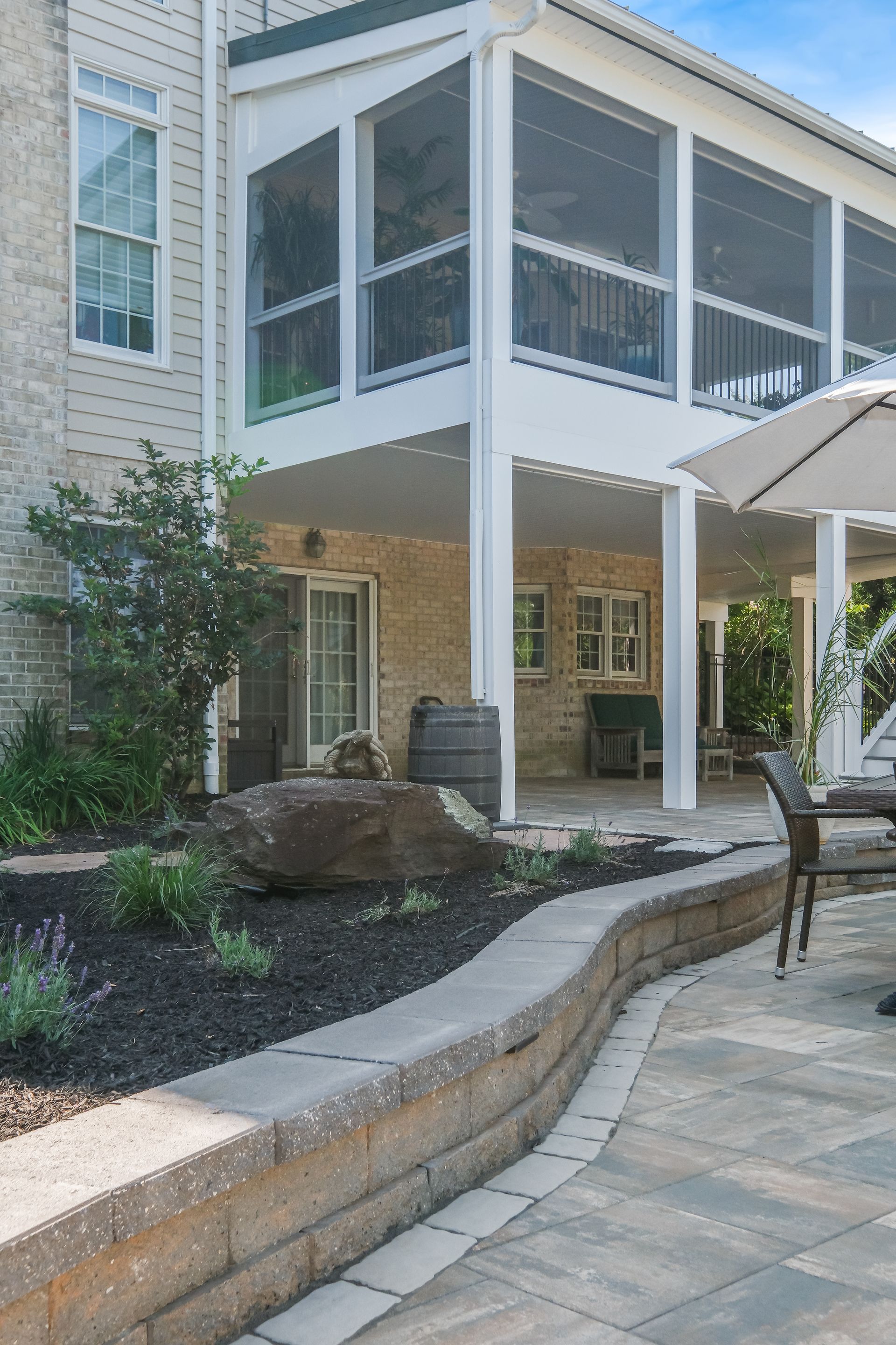 A screened in porch with a table and chairs and an umbrella.