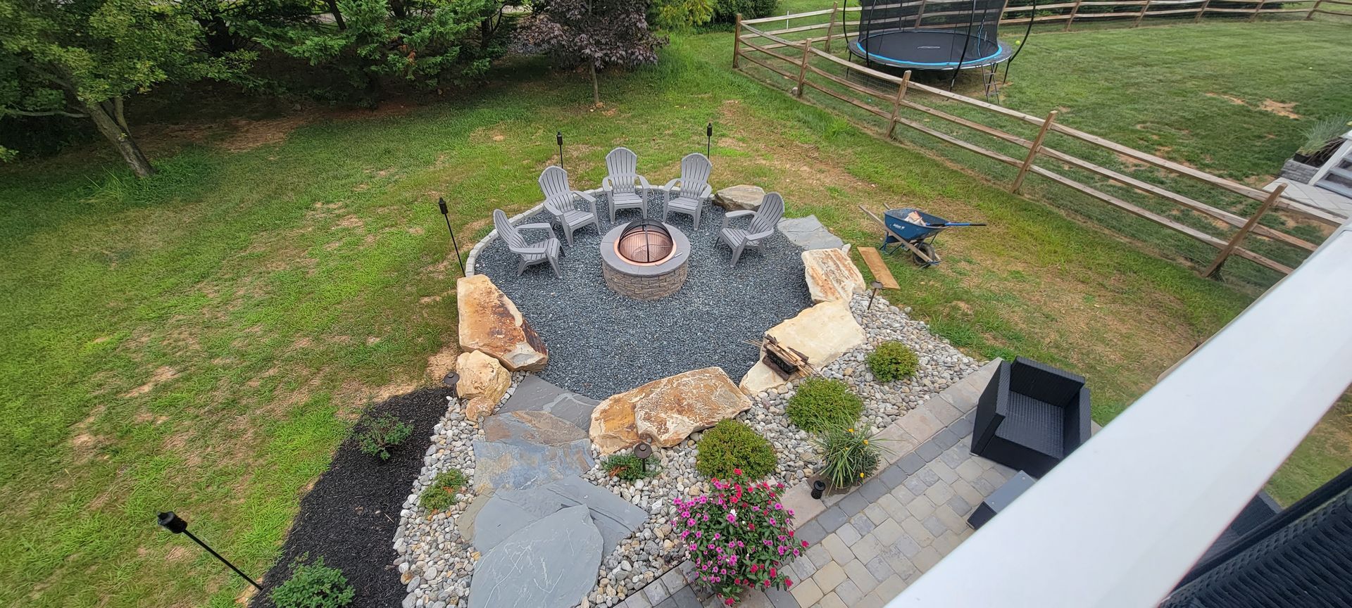 An aerial view of a backyard with a fire pit and chairs.