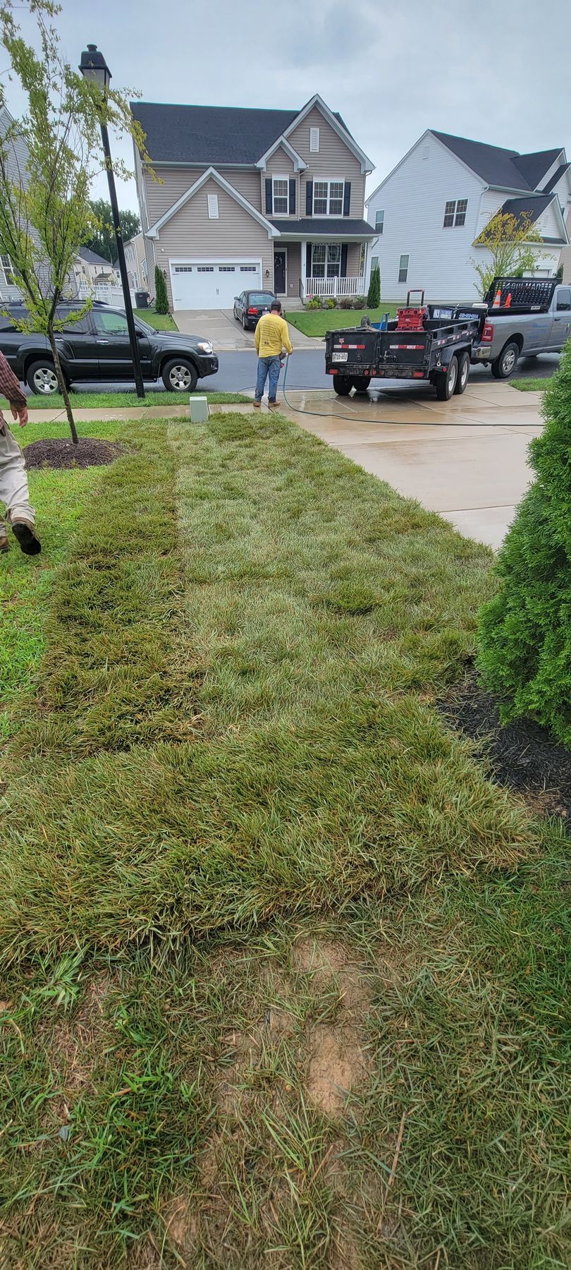 A man is mowing the grass in front of a house.
