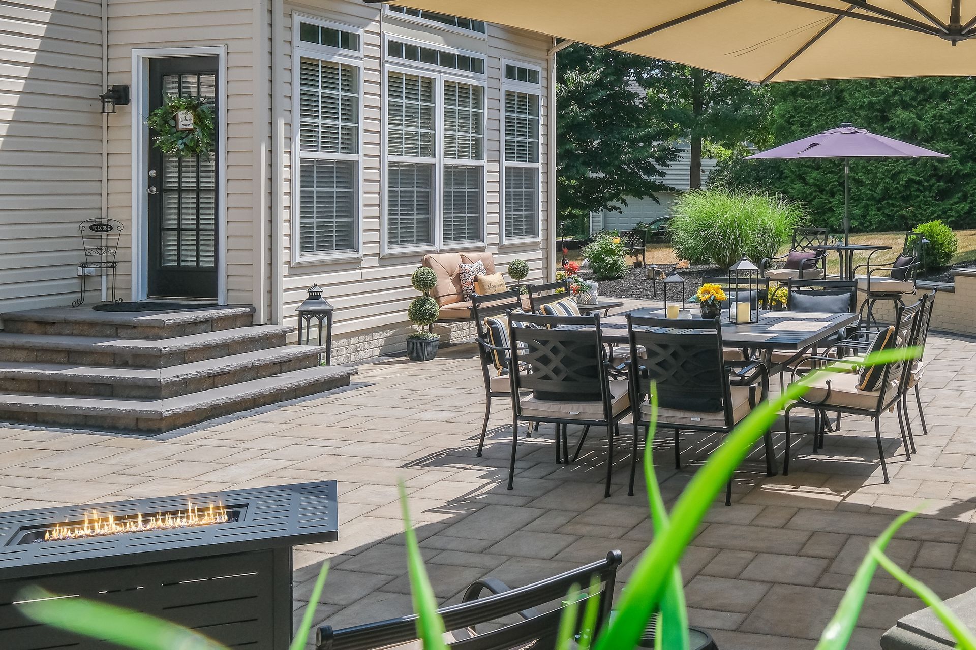 A patio with a table and chairs and an umbrella in front of a house.