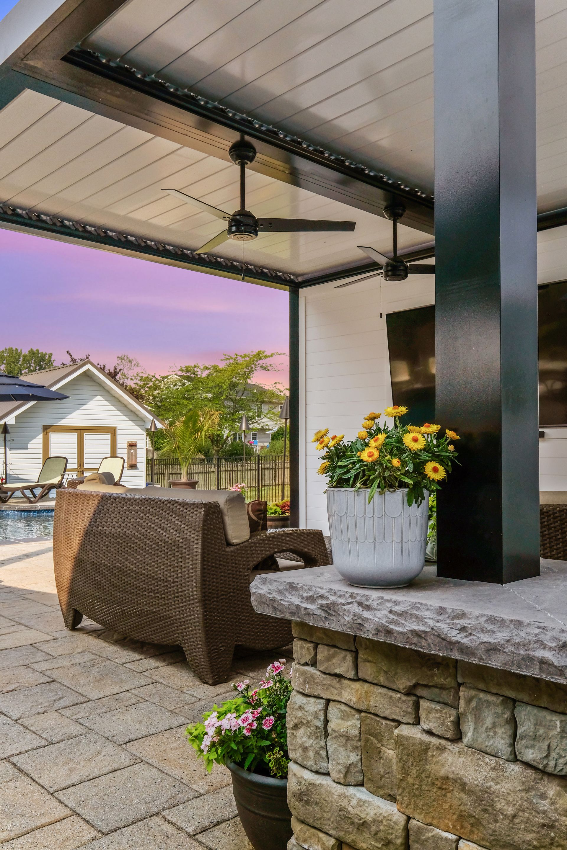 A patio with a ceiling fan and a potted plant on the counter.