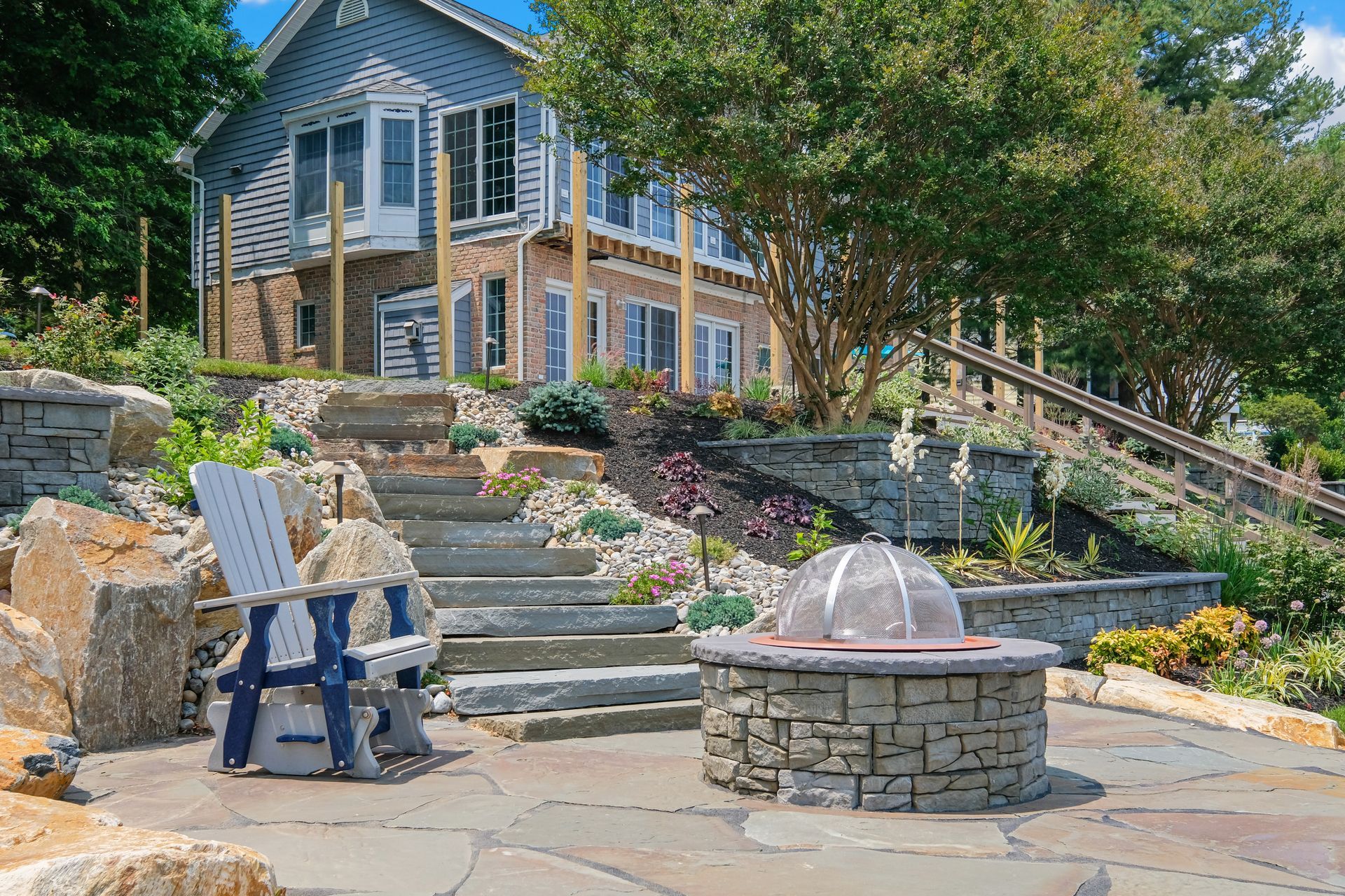 There is a fire pit in the middle of the patio in front of a house.