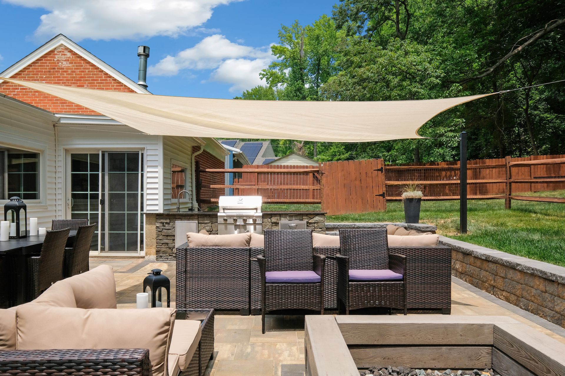 A patio with wicker furniture and a fire pit under an umbrella.