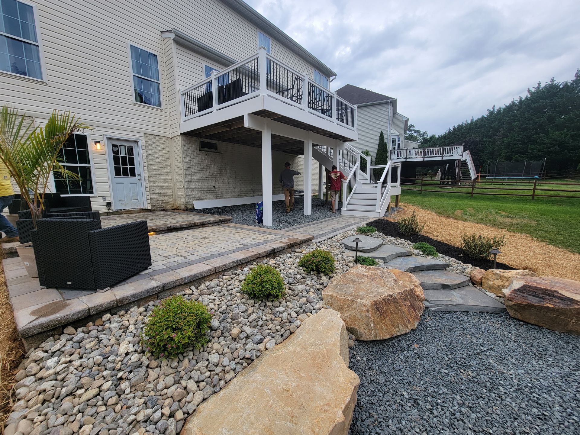 The backyard of a house with a large deck and stairs leading to it.