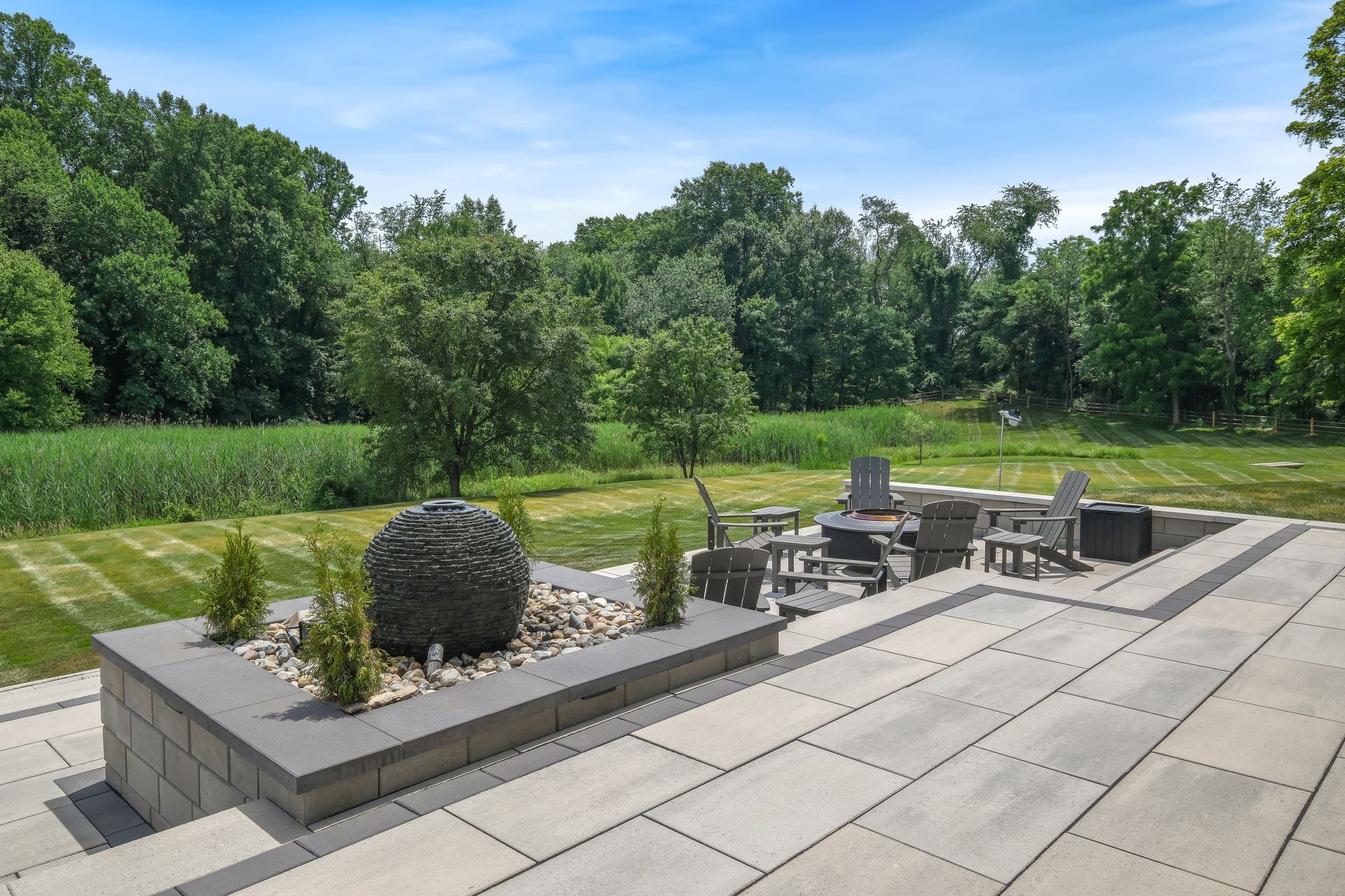 A fountain in the middle of a patio with trees in the background.