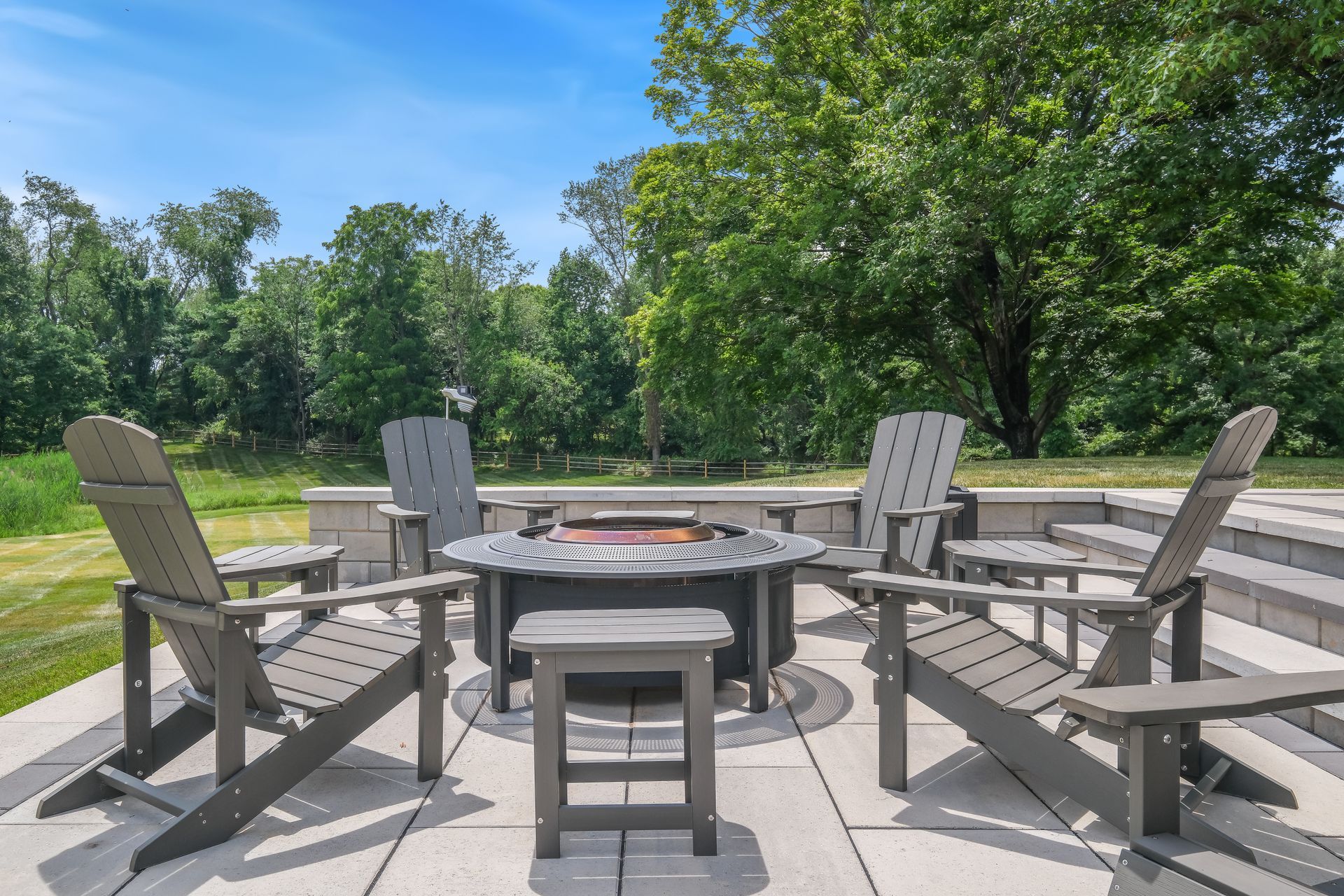 A group of chairs are sitting around a fire pit on a patio.