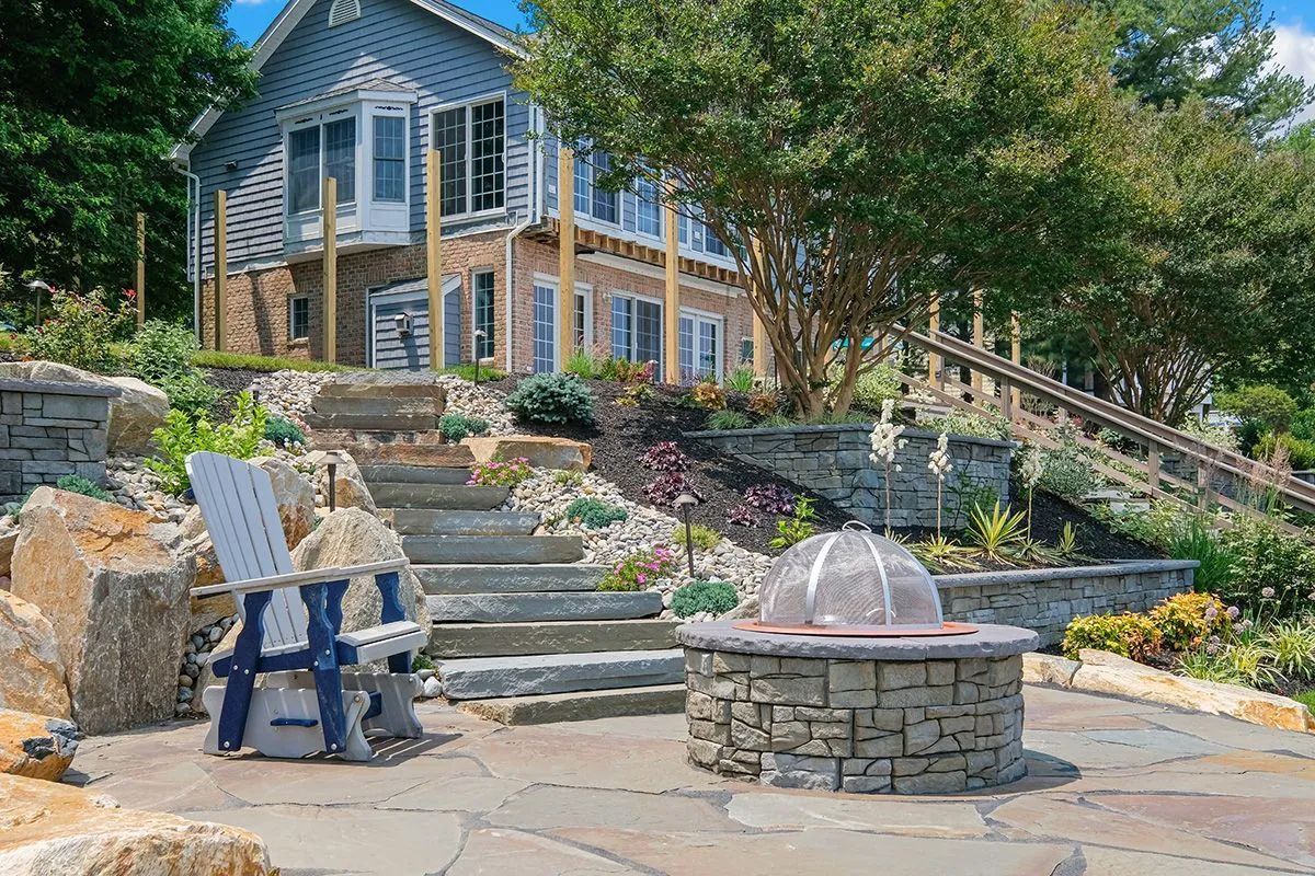 There is a fire pit in the middle of the patio in front of a house.