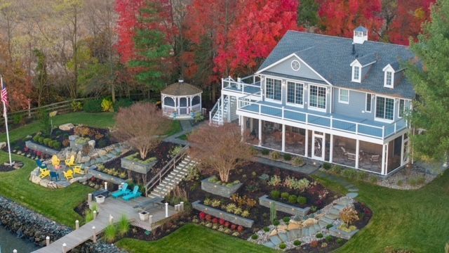 An aerial view of a large house surrounded by trees and a dock.