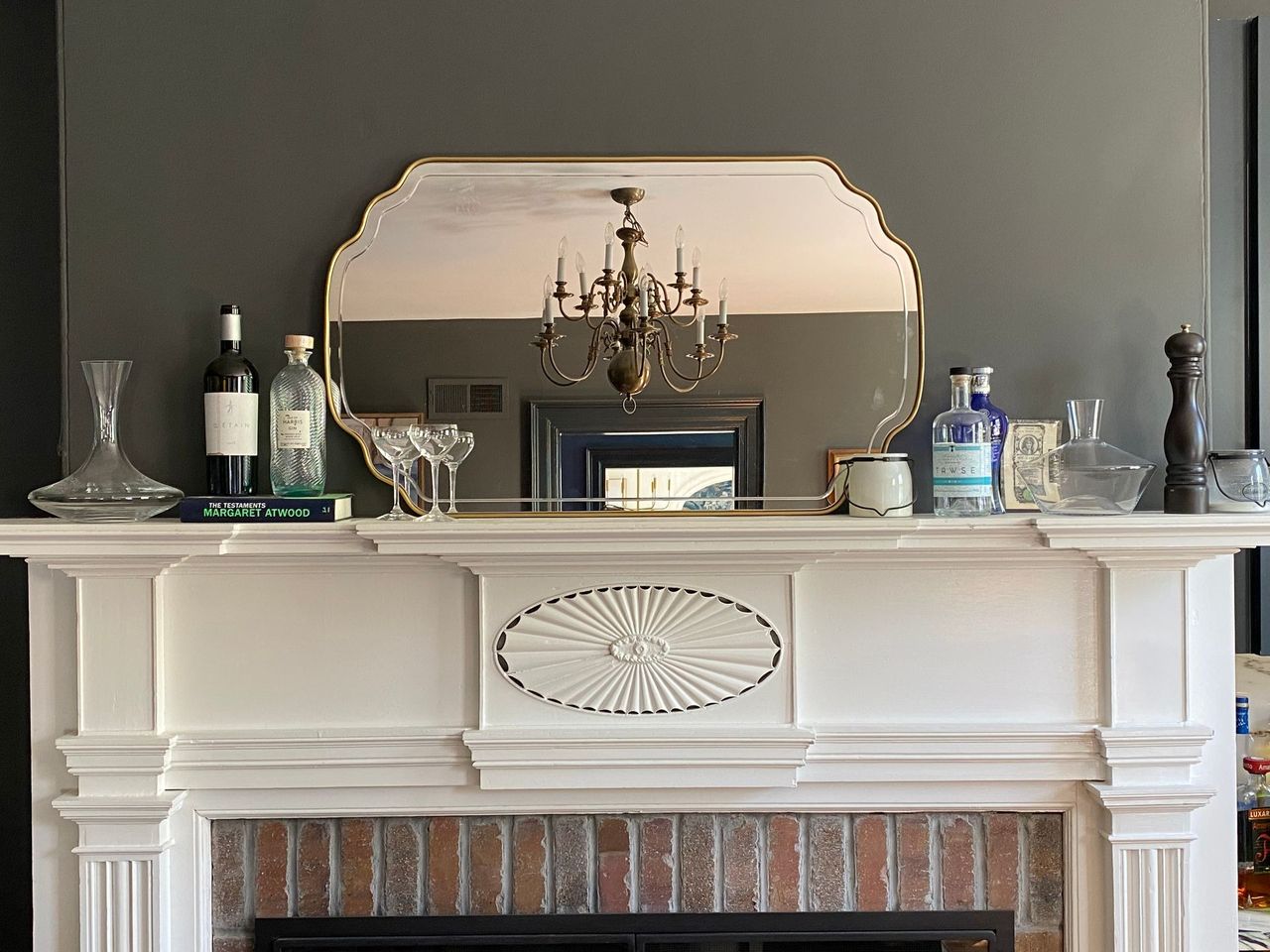 Fireplace with white mantel, mirror, and decorative items; dark gray wall.