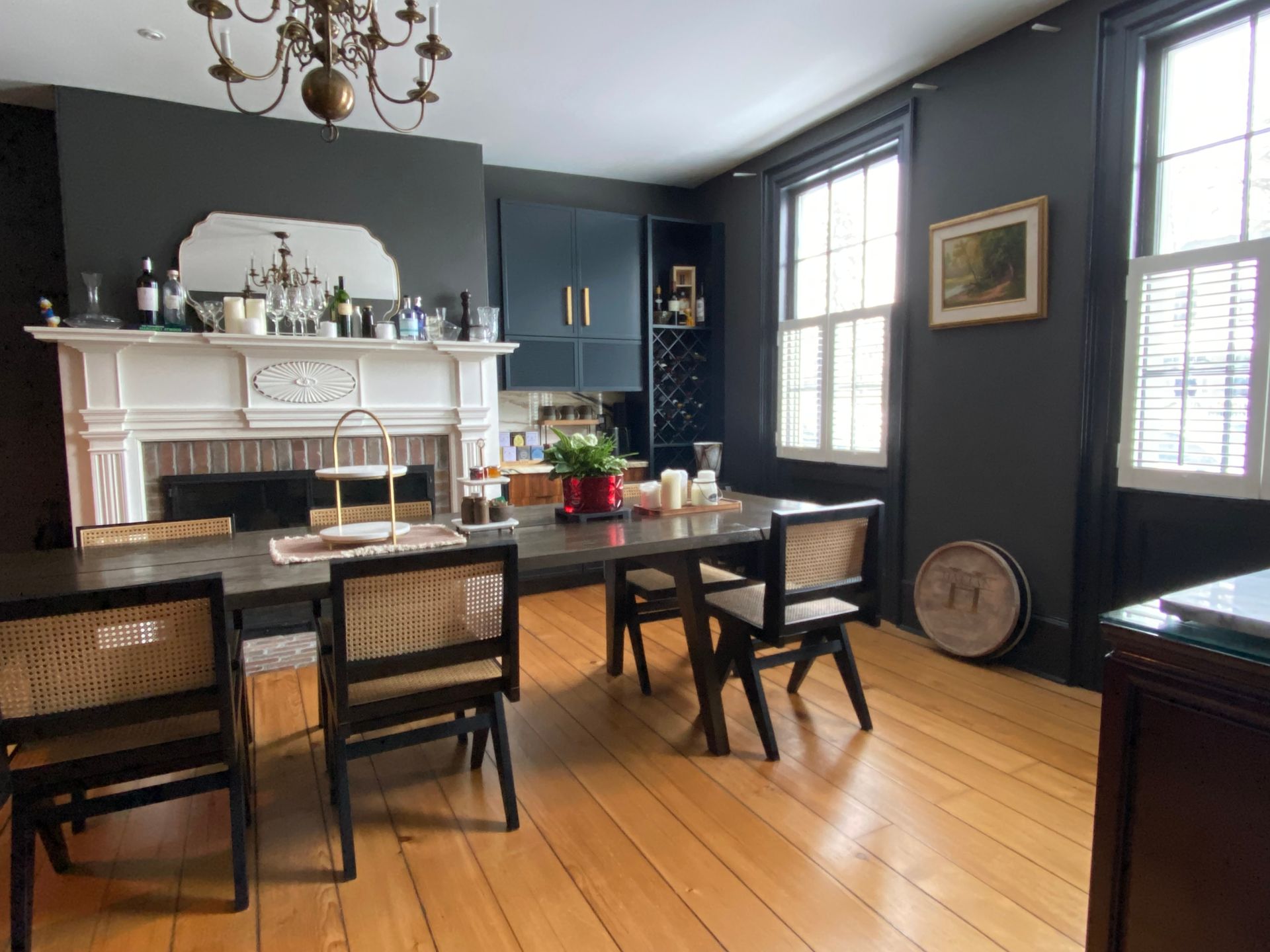 Dining room with gray walls, wood floors, table, chairs, fireplace, and chandelier.
