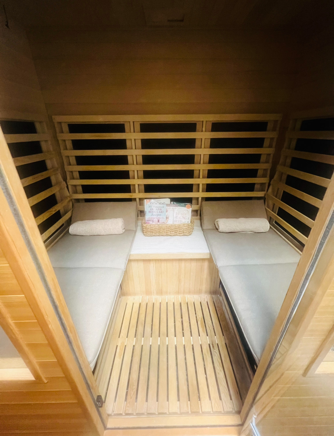 A wooden infrared sauna is sitting in a room next to a chair.