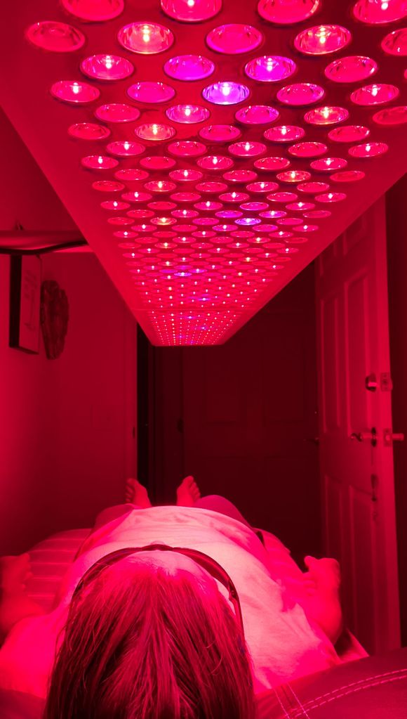 A red light is shining on a yoga mat in a living room.