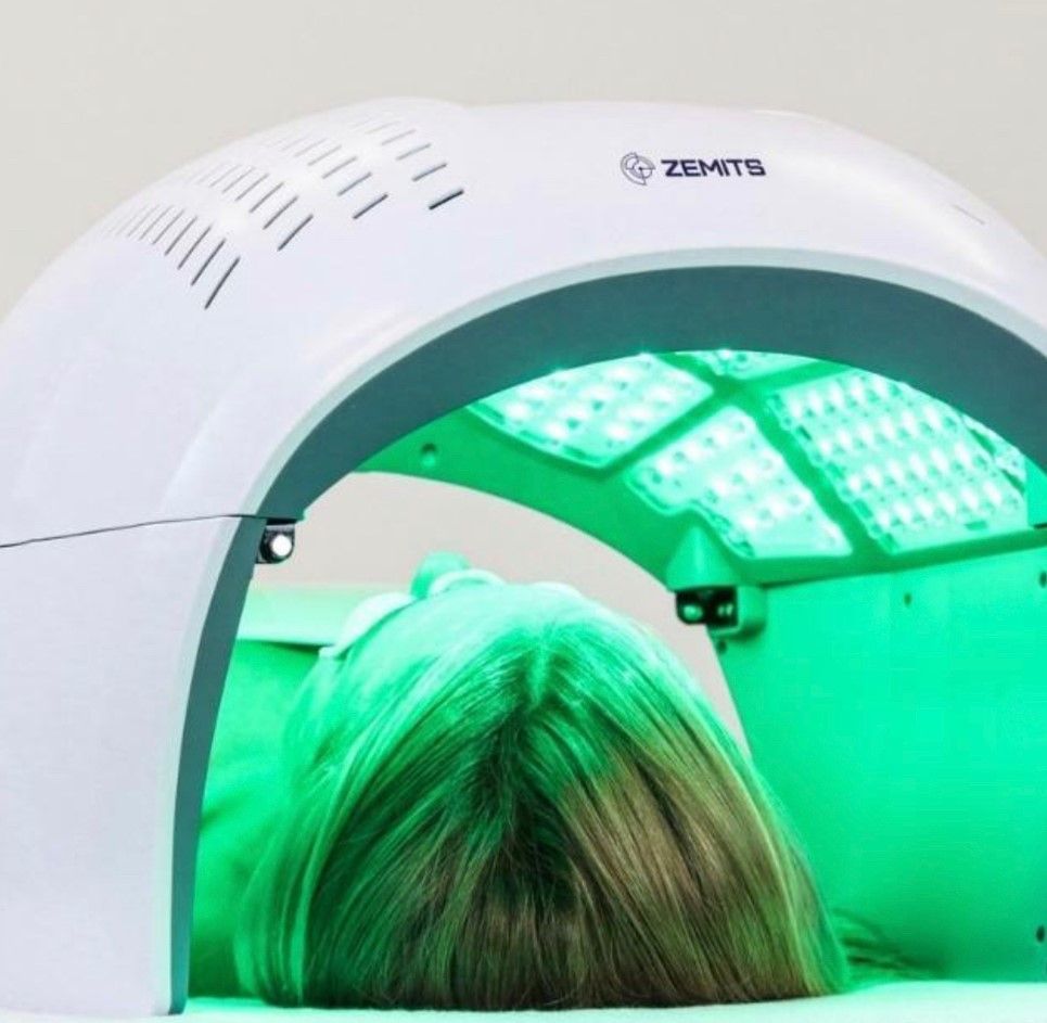 A woman is laying under a green led light device