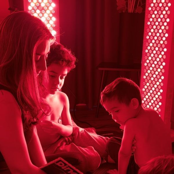 A woman is reading a book to two children under red lights