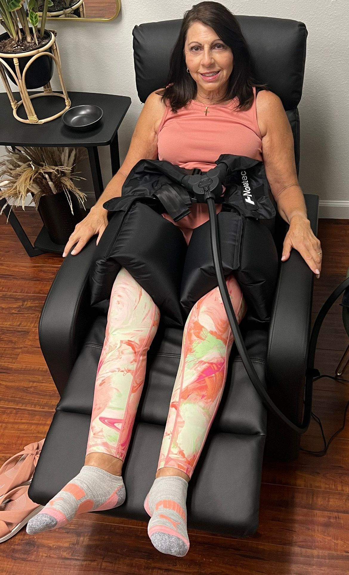 A woman is sitting in a chair with a machine on her legs.