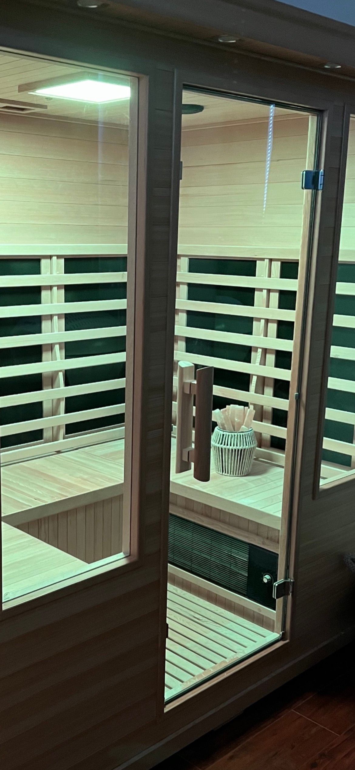 A wooden sauna with a glass door.