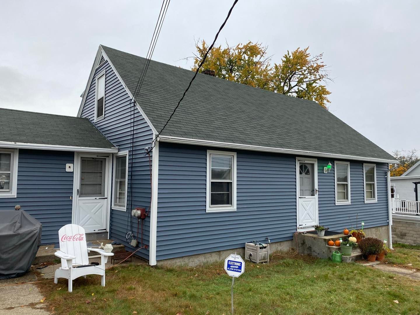 Blue house with white doors, window and trim. A Coca-Cola chair and fall decorations are in the yard.