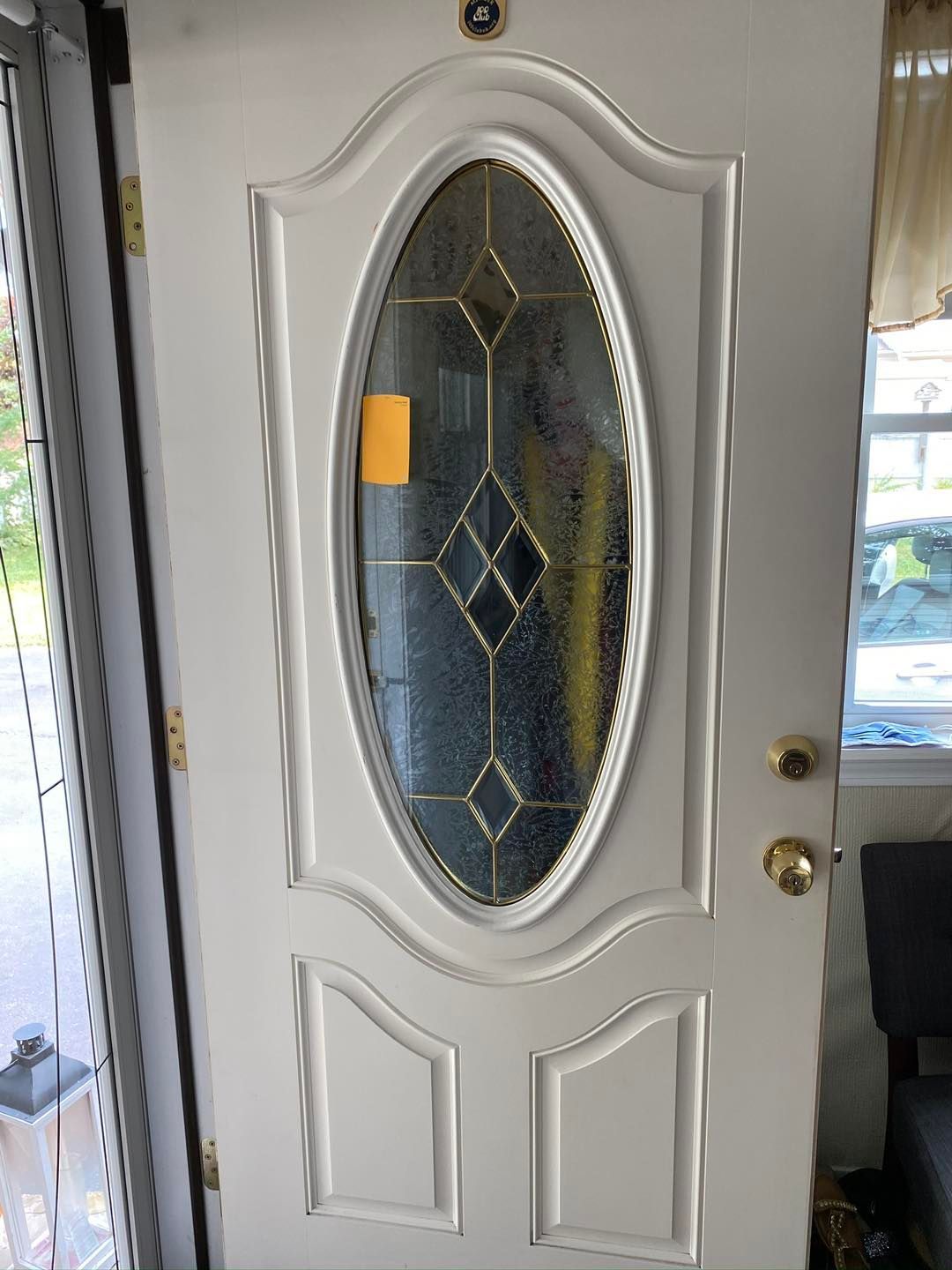 White front door with oval glass panel. Gold trim and decorative panels.