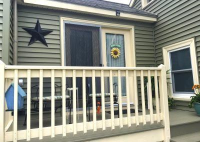 Green house with white porch, sliding glass door, and star decor.
