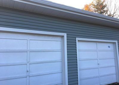 Two white garage doors with blue siding, trimmed in white.