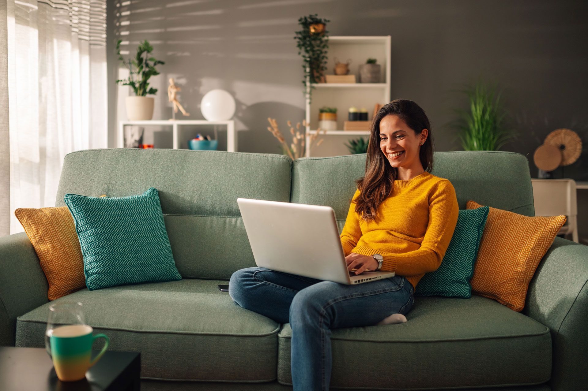 A woman is sitting on a couch using a laptop computer.