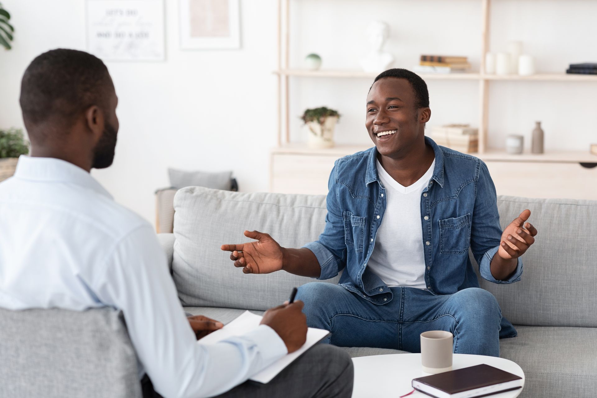 A man is sitting on a couch talking to another man.