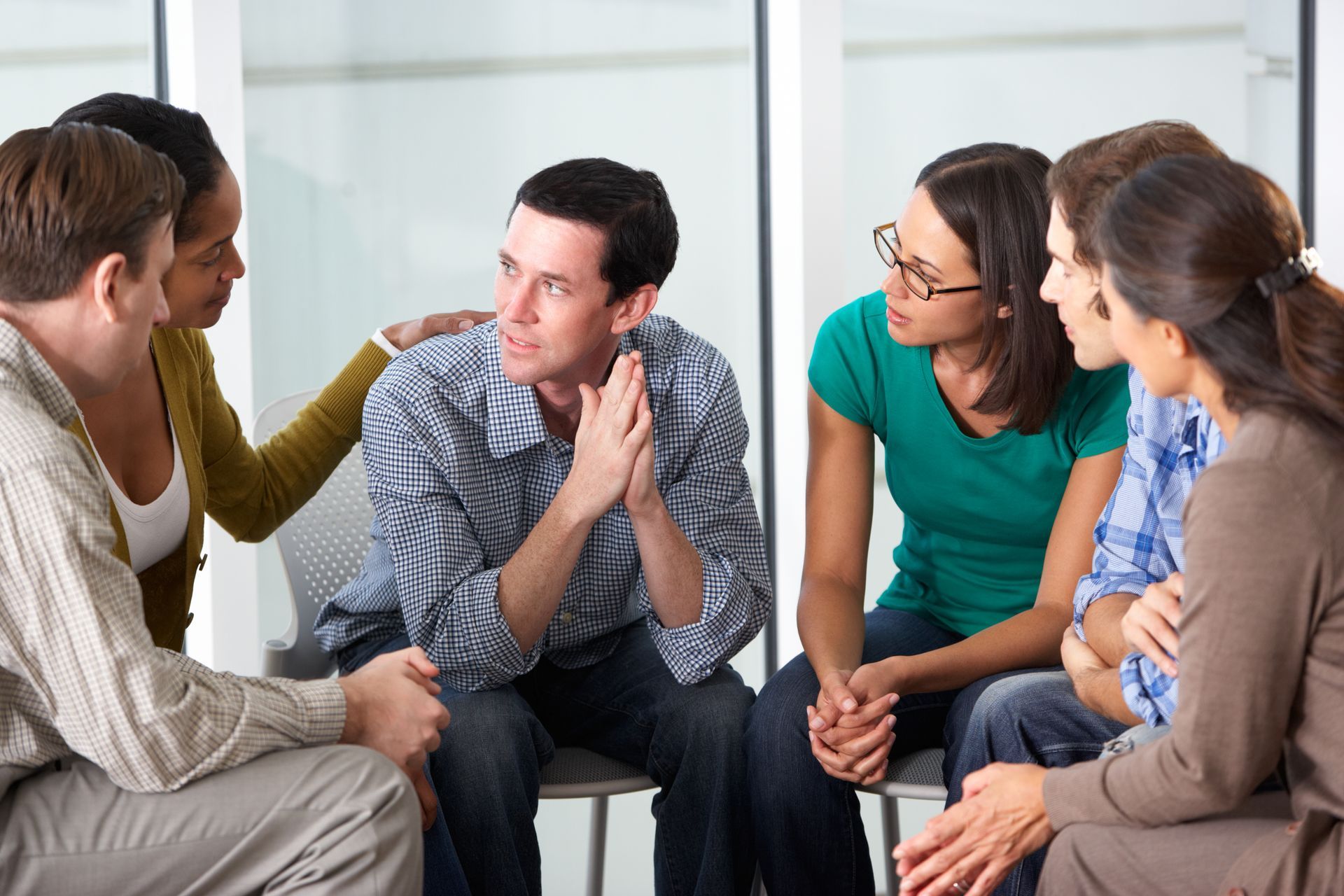 A group of people are sitting in a circle talking to each other.
