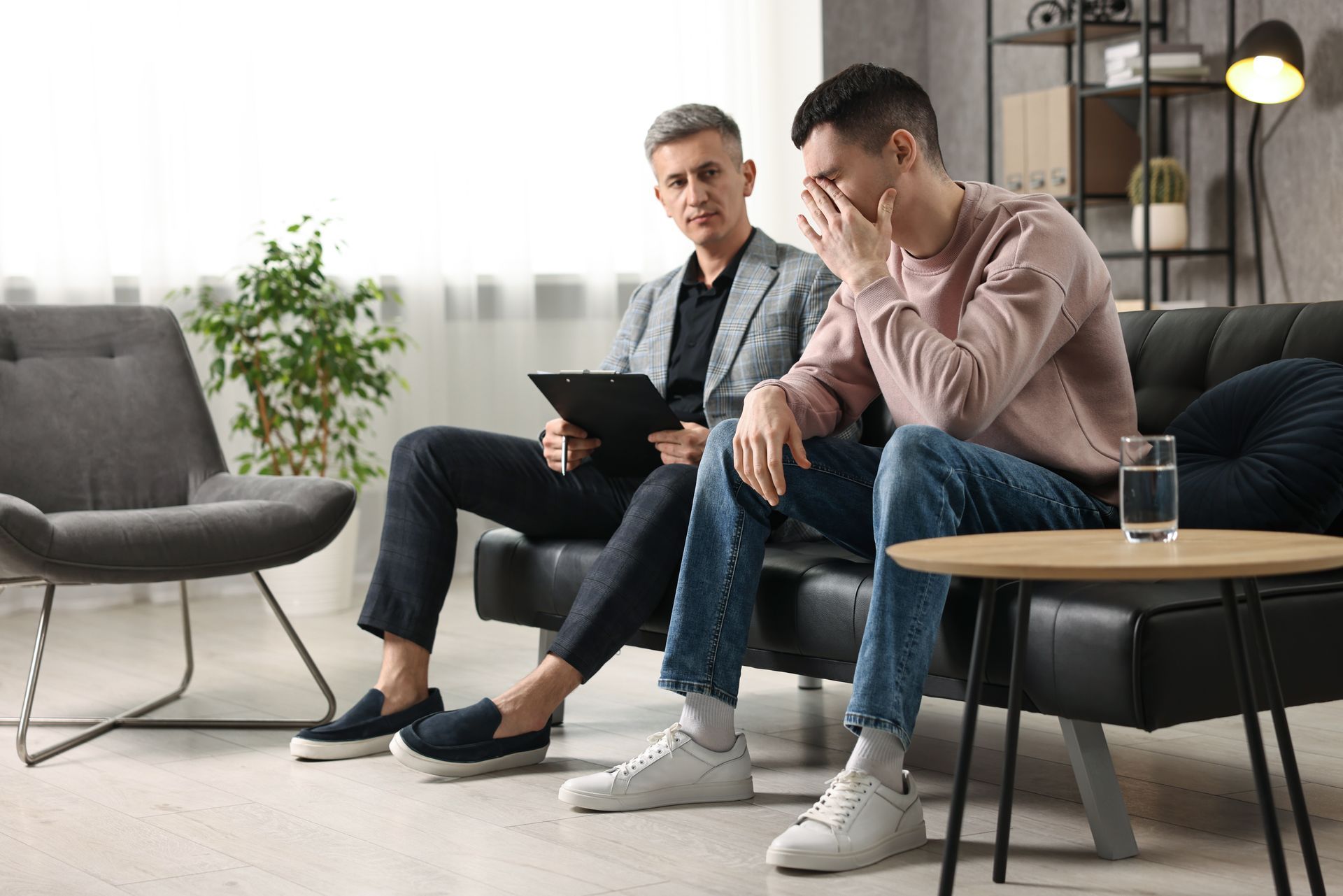 A man is sitting on a couch talking to another man.