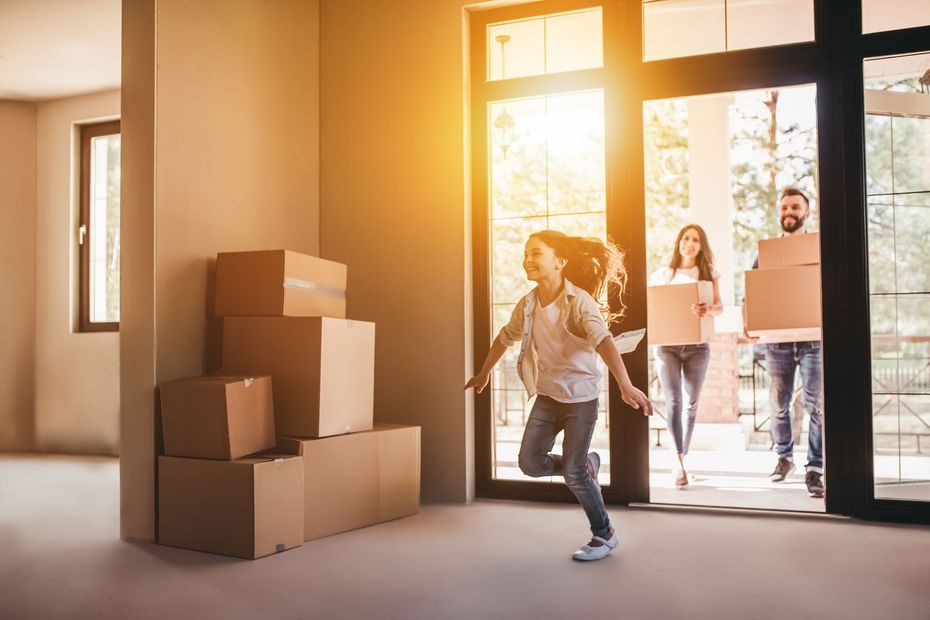 People moving boxes into a bright, empty room through a glass door People moving boxes into a bright, empty room through a glass door