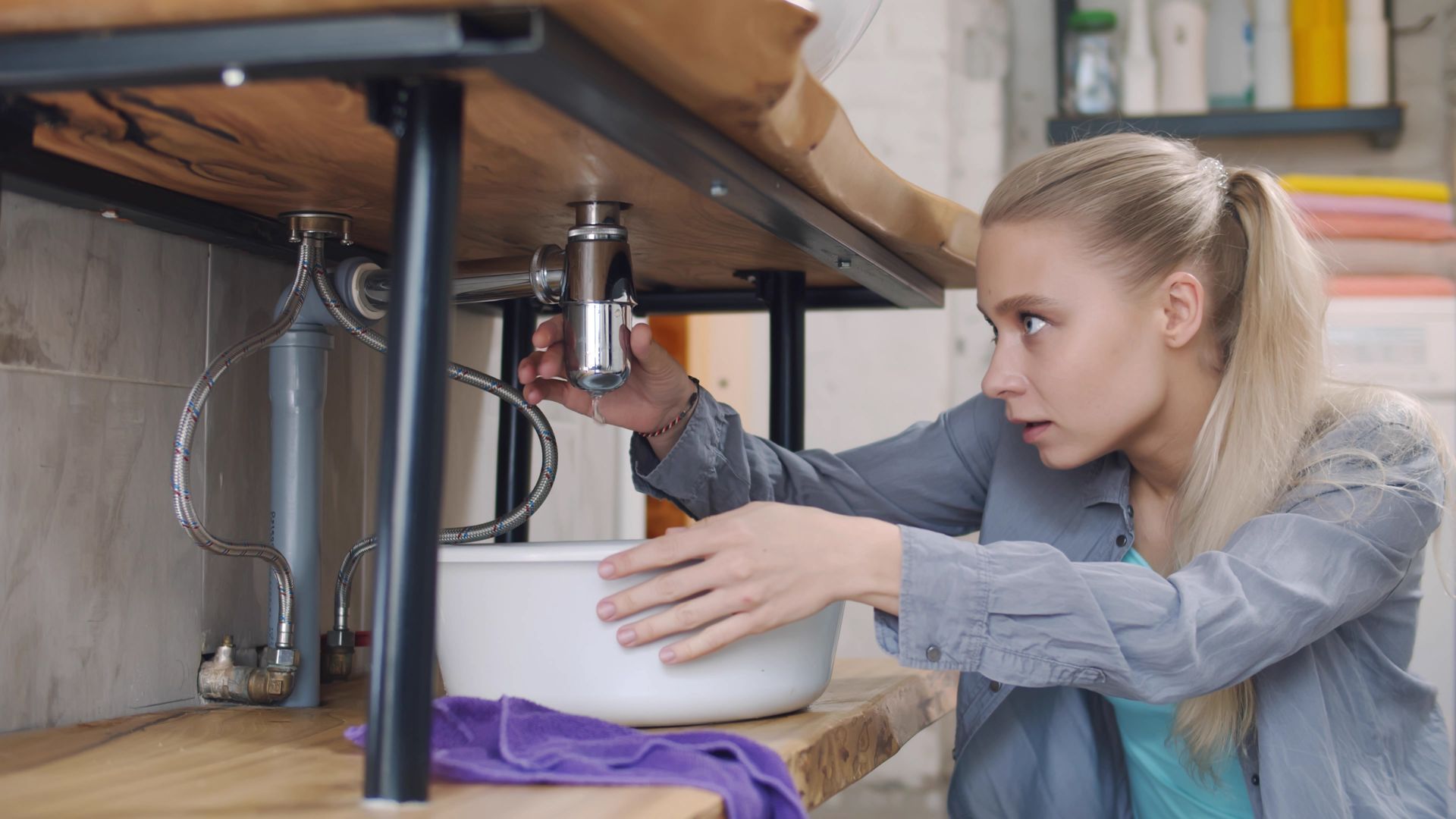 Woman installing a kitchen filter under a sink, holding a wrench and adjusting plumbing pipes. Woman installing a kitchen filter under a sink, holding a wrench and adjusting plumbing pipes.