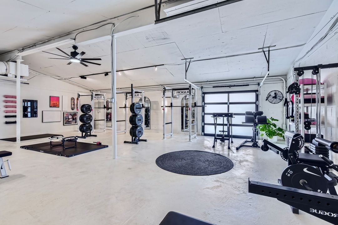 A gym with a lot of equipment and a ceiling fan.