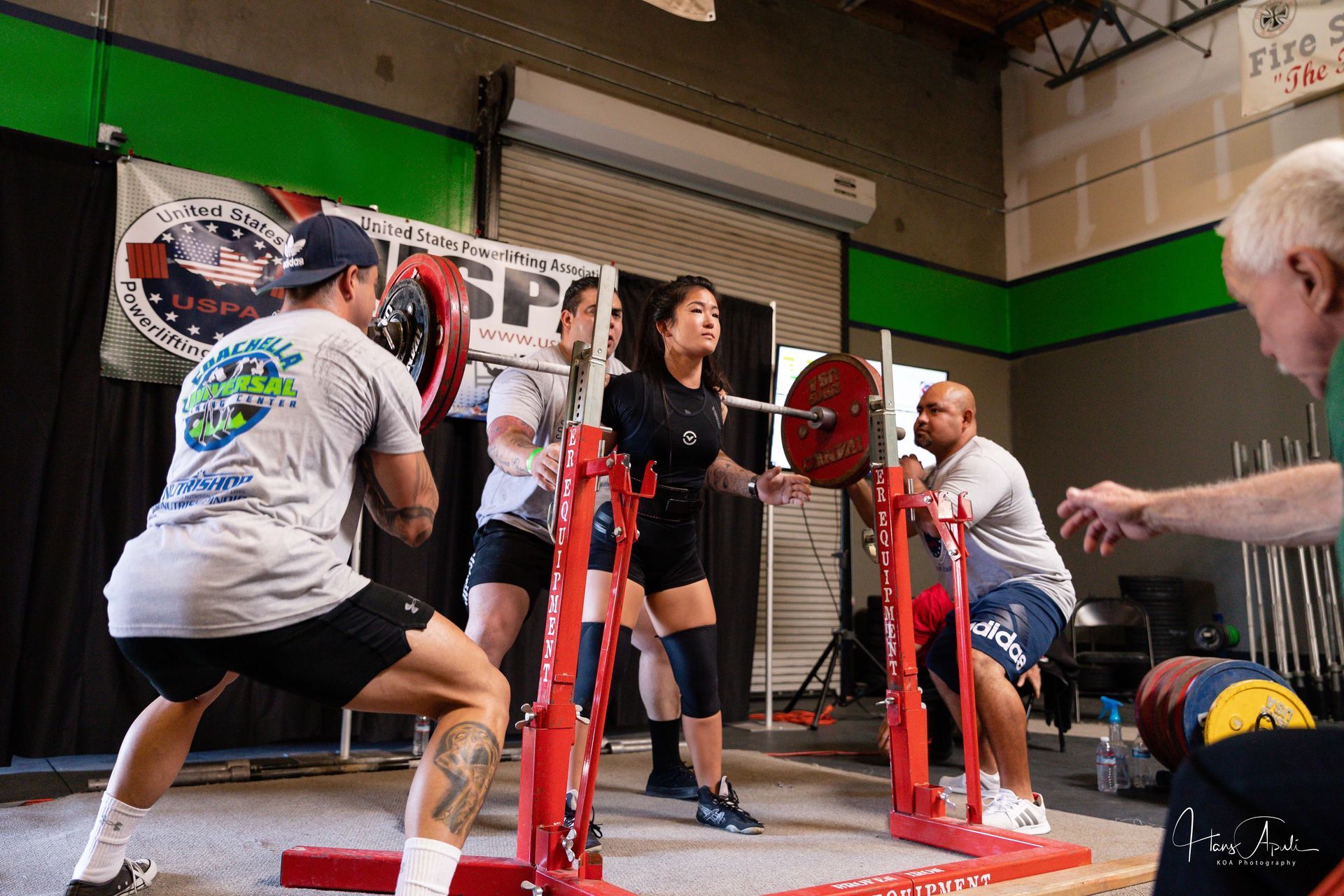 A picture of a woman squatting on squat racks in a gym.