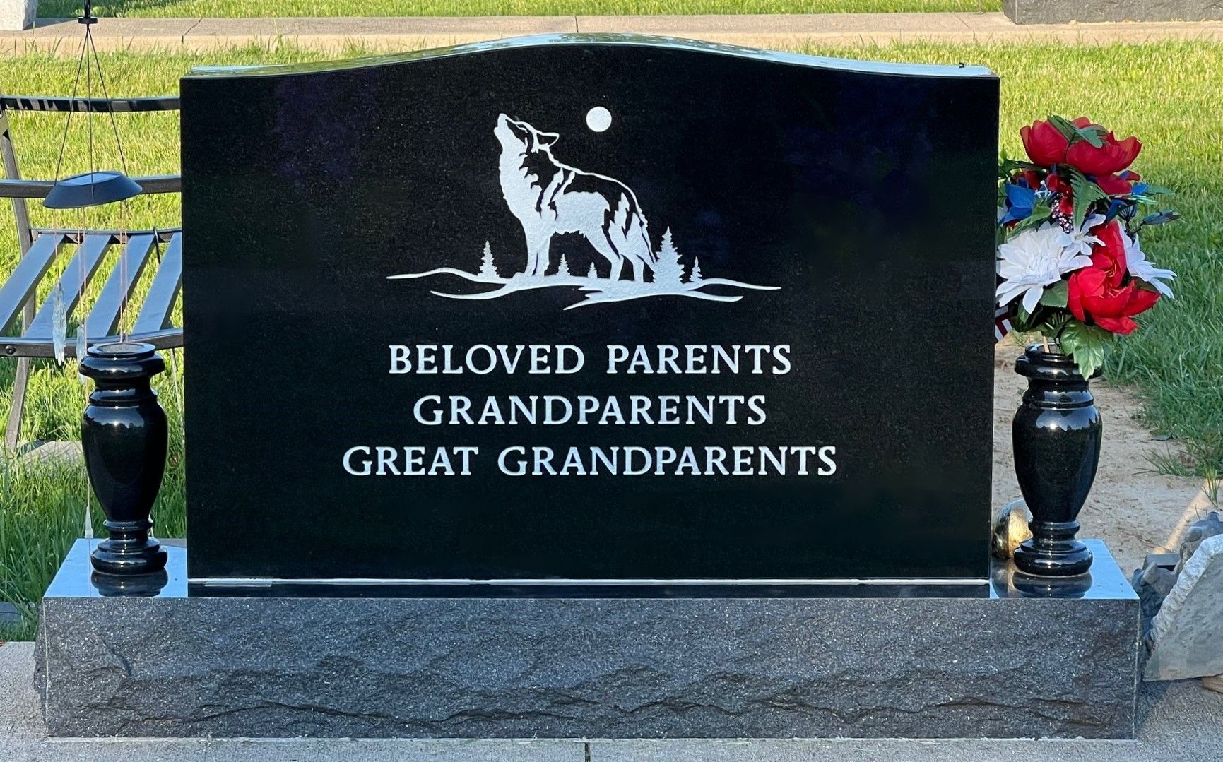 A black gravestone with a wolf on it that says beloved parents grandparents great grandparents