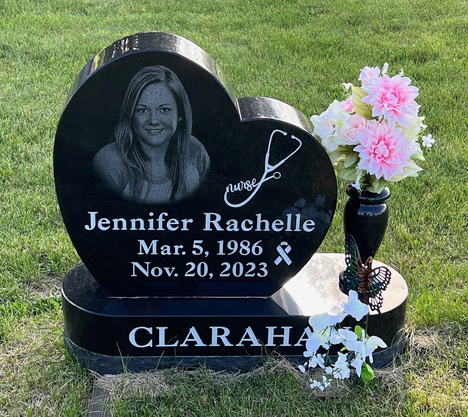 A black heart shaped gravestone with a picture of a woman on it