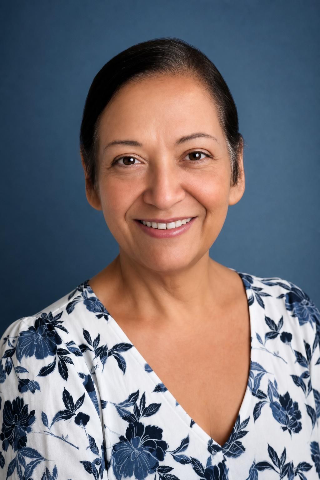Smiling woman in a white floral blouse against a blue studio background
