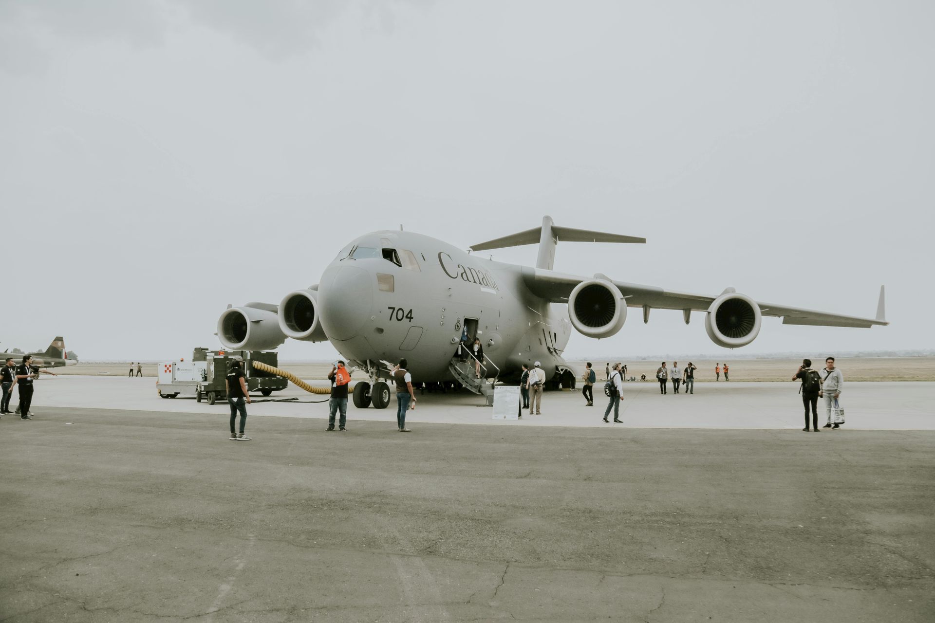 People standing around a large military cargo plane on a gray runway