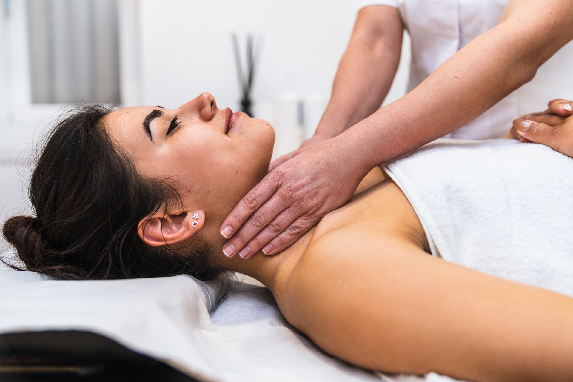 A woman is laying on a bed getting a reiki treatment.