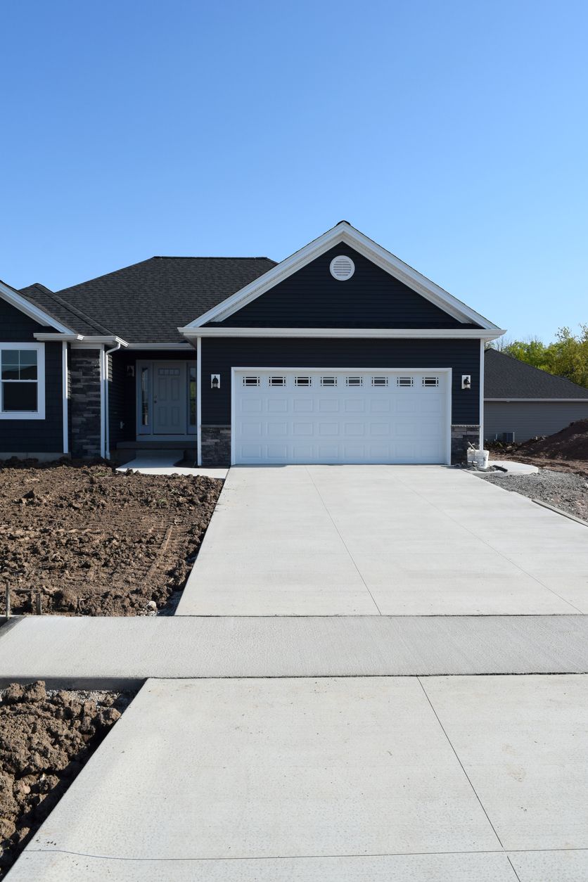A black house with a white garage door and a concrete driveway