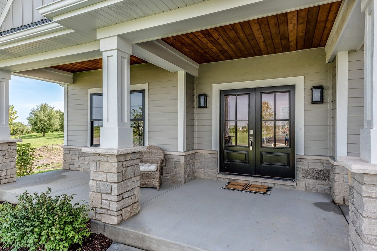 The front porch of a house with a chair and a rug on it.