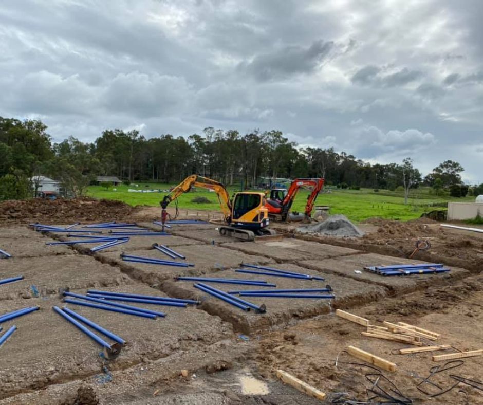 Screw pile shed foundation installation with excavators on site.