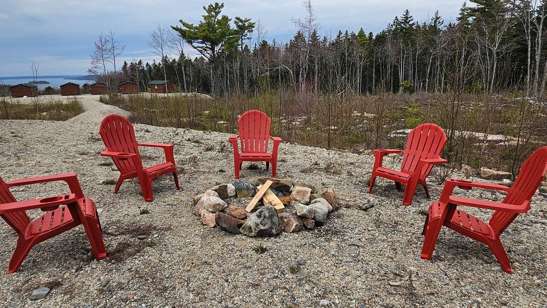 A group of red chairs are sitting around a fire pit.