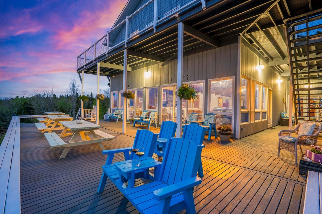 A deck with blue chairs and tables and a building in the background.